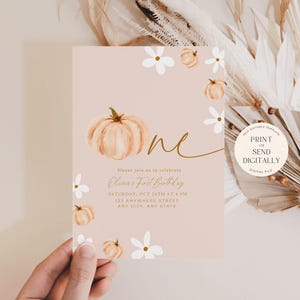 Pu&ograve; includere: Un invito di compleanno rosa cipria con una zucca ad acquerello e la parola "one" in corsivo dorato. L'invito include i dettagli per una festa di primo compleanno, con accenti floreali e di zucca. Il design &egrave; per un file digitale.