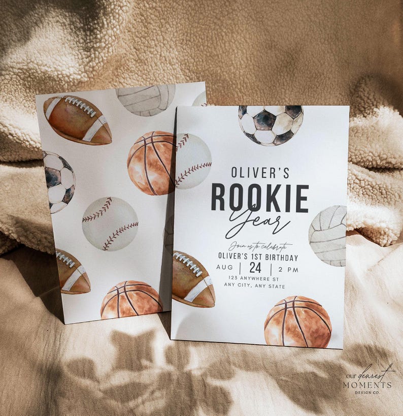May include: A white invitation with a watercolor illustration of sports balls, including a basketball, baseball, football, soccer ball, and volleyball. The text on the invitation reads "Oliver's Rookie Year" and includes details for a first birthday party.