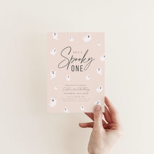 May include: A pink invitation with a white ghost pattern. The text reads "He's a Spooky One" and includes details for Easton's first birthday party.