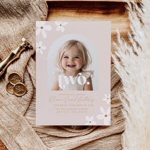 May include: A pink and white birthday invitation with a photo of a young girl. The invitation says "Olivia's Second Birthday" and includes the date, time, and location of the party. The invitation is decorated with white daisies.