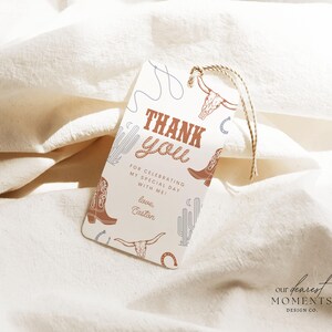 May include: A white thank you tag with brown and blue illustrations of cowboy boots, cacti, and a lasso. The text reads "Thank you" in brown letters and "For celebrating my special day with me! Love, Easton".