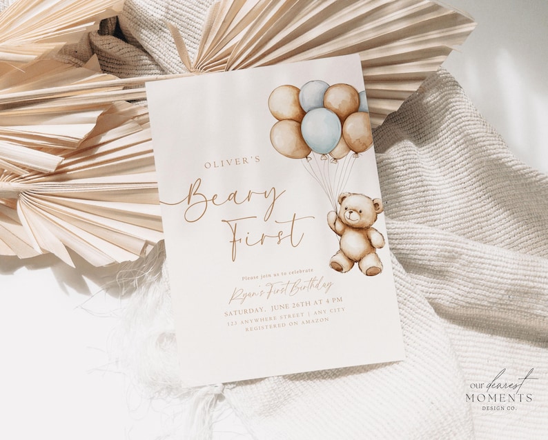 May include: A beige invitation card with brown text that reads "Oliver's Beary First" and "Ryan's First Birthday". The card features a watercolor illustration of a teddy bear holding balloons.
