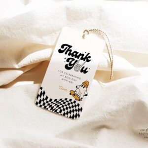 May include: Thank you tag with a checkered background and a ghost on a skateboard. The text reads "Thank You" in a retro font with a ghost holding a skateboard and the words "For celebrating my boo-day with me!"  The tag is tied with twine.