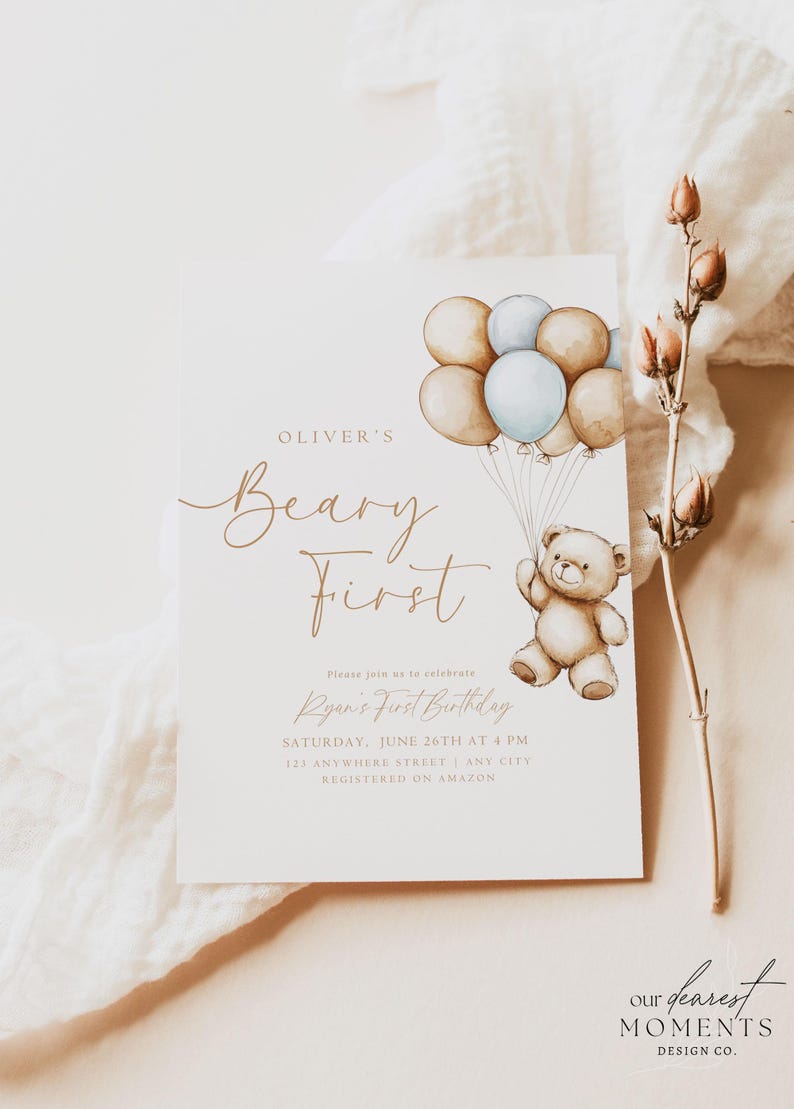May include: A light brown teddy bear holding onto blue and brown balloons. The invitation reads "Oliver's Beary First" and includes the text "Please join us to celebrate Ryan's First Birthday, Saturday, June 26th at 4 PM, 121 Anywhere Street, Any City, Registered on Amazon". The bottom of the invitation reads "Our Dearest Moments Design Co."