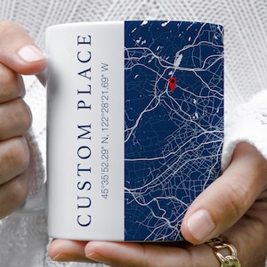 May include: White ceramic mug with a navy blue map design and the words "CUSTOM PLACE" in navy blue. The mug also includes the coordinates 45°35'52.29" N, 122°28'21.69" W. A red marker pinpoints a location on the map.