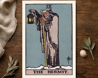 Może przedstawiać: Prostokątna karta tarota przedstawiająca Pustelnika, oznaczona IX i THE HERMIT. Ilustracja ukazuje brodatą postać w długim szarym płaszczu, trzymającą żółtą laskę i świecącą latarnię na niebieskim tle z białymi, ośnieżonymi szczytami górskimi.