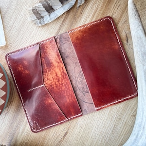 May include: A red leather wallet with white stitching and multiple pockets. The wallet is open and the inside is visible.