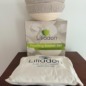 Op de afbeelding: Een proofing mand set van Liliadon, gemaakt van luxe Indonesisch rotan. De set bevat twee beige met linnen gevoerde manden en een canvas tas met het Liliadon logo en website adres. De doos leest "Proofing Basket Set".
