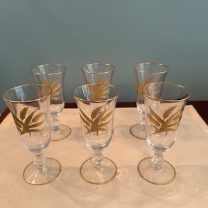 Op de afbeelding: Set van zes heldere glazen champagnefluiten met bladgouden accenten. Elke fluit heeft een gestileerd bladontwerp.