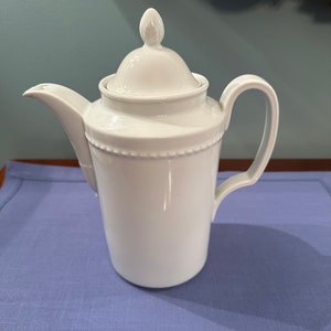 May include: White porcelain coffee pot with a lid and a beaded design around the body.