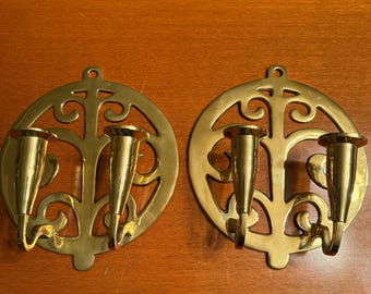 May include: A pair of gold metal candle holders with a decorative, ornate design. Each holder has three candle slots.