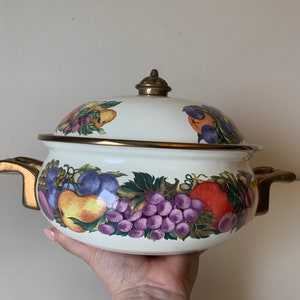 May include: White enamel pot with a gold rim and handles. The pot is decorated with a colourful fruit design, including grapes, pears, and apples.