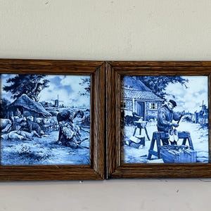 Può includere: Due piastrelle di Delft blu e bianche incorniciate che raffigurano scene della vita olandese. La piastrella di sinistra mostra una donna e un uomo che lavorano con le pecore in un campo. La piastrella di destra mostra un uomo che fa zoccoli di legno in un laboratorio.