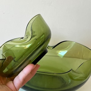 Può includere: Un set di due ciotole di vetro verde con una forma ondulata e organica. La ciotola più piccola si inserisce nella più grande.