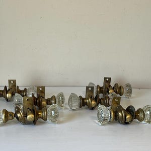 May include: A collection of vintage glass door knobs with brass fittings. The clear glass knobs feature a ribbed design, and the brass components show signs of age. These antique door knobs are a classic addition to any home.