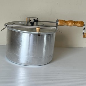 Op de afbeelding: Een witte keramische mok met een zwarte handgreep en de tekst "But First, Coffee" in een vetgedrukte, zwarte letter. De mok staat tegen een vage achtergrond, wat een gezellige setting suggereert.