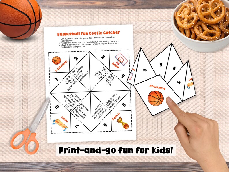 Puede incluir: Un juego de adivinanzas con tem&aacute;tica de baloncesto con una pelota de baloncesto, tijeras y un cuenco de pretzels. El juego incluye instrucciones y preguntas. El texto de la imagen dice: "Print-and-go fun for kids!"
