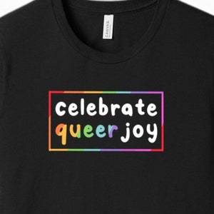 May include: Black t-shirt with a rainbow-colored box around the text "celebrate queer joy".