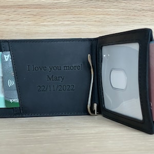 May include: Black leather wallet with a money clip and a clear ID window. The wallet has a personalized message that reads "I love you more! Mary 22/11/2022".