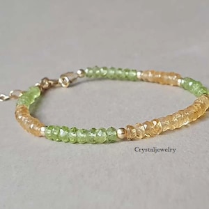 May include: A delicate gold bracelet with alternating green and orange gemstone beads. The bracelet is made with small, faceted beads and has a simple clasp.