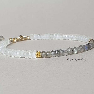 Könnte beinhalten: Ein weißes und graues Perlenarmband mit goldenen Akzenten. Das Armband besteht aus weißen Mondstein- und Labradoritperlen.