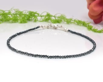 May include: A delicate silver chain bracelet with small, dark grey hematite beads.