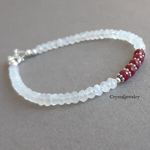 May include: A white moonstone bracelet with a row of red ruby beads and silver accents. Crystaljewelry.