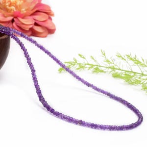 May include: A delicate necklace made with small, faceted amethyst beads. The necklace is strung on a clear thread and is approximately 18 inches long.