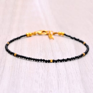 Op de afbeelding: Een delicate armband van zwarte onyx en gouden kralen. De armband is gemaakt met kleine zwarte onyx kralen en gouden accenten.