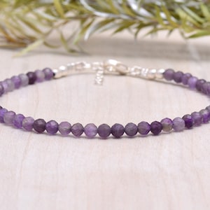 Könnte beinhalten: Ein zartes Amethyst-Armband mit einem silbernen Verschluss. Das Armband besteht aus kleinen, facettierten Amethystperlen und ist etwa 18 cm lang.
