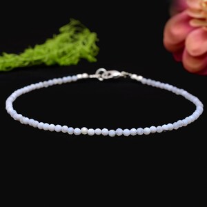 Könnte beinhalten: Ein zartes Armband aus blauem Chalcedon mit einem silbernen Verschluss. Das Armband besteht aus kleinen, runden Perlen und ist etwa 18 cm lang.