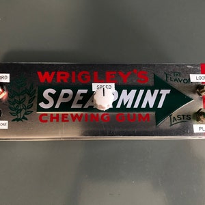 Könnte beinhalten: Eine silberne Metallbox mit einem Wrigley's Spearmint Kaugummi-Etikett. Die Box hat einen roten Knopf mit der Aufschrift "Record", einen schwarzen Knopf mit der Aufschrift "Microphone", einen weißen Knopf mit der Aufschrift "Speed", einen grünen Knopf mit der Aufschrift "Play" und einen roten Knopf mit der Aufschrift "Loop".