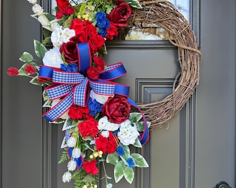 Corona patriótica de vid con flores rojas, blancas y azules y lazo de cuadros vichy.