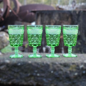 May include: A white ceramic mug with a black handle and the text "But First, Coffee" in a bold, black font. The mug is set against a neutral background, highlighting its simple design.