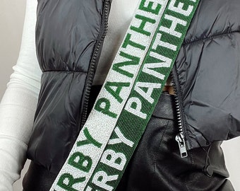 May include: A white and green beaded bag strap with the text "Derby Panthers" repeated on both sides.