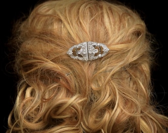May include: A silver hair comb with clear rhinestones in an oval shape.