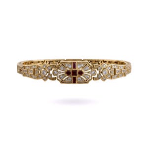 Könnte beinhalten: Ein goldenes Armband mit einer zentralen rechteckigen Platte, die mit drei dunkelroten Rubinen in Kreuzform besetzt ist, umgeben von kleinen klaren Diamanten. Das Band besteht aus komplexen geometrischen Goldgliedern und weiteren Diamantakzenten.