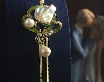 May include: A gold hair stick with a pearl and green enamel flower design. The stick has two prongs and is decorated with small pearls.