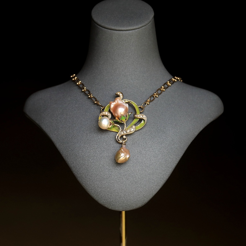 May include: A gold necklace with a pink and green enamel flower pendant and pearl accents.