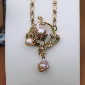 May include: A gold necklace with a pendant featuring a pearl flower with green enamel accents and a dangling pearl drop.
