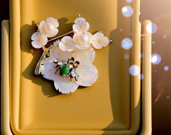 Superb Art Nouveau brooch featuring a branch of small and large flowers, white mother-of-pearl, a bee, and a green jade bead. Vintage style, gold plated.