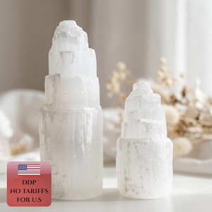 Può includere: Due torri di cristallo di selenite bianca con una consistenza fibrosa traslucida e cime irregolari a strati. La torre più alta si trova a sinistra, mentre una torre più piccola e simile è posizionata a destra. È presente un piccolo grafico.