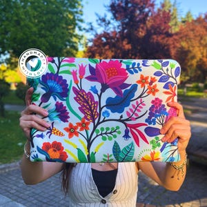 May include: A white laptop sleeve with a colorful floral pattern. The sleeve has a white circle with the text "Handmade with Love" in black.
