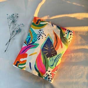May include: A white canvas pouch with a colorful abstract floral print. The print features bright pink, blue, green, and yellow colors. The pouch is perfect for carrying small items like makeup, jewelry, or phone.
