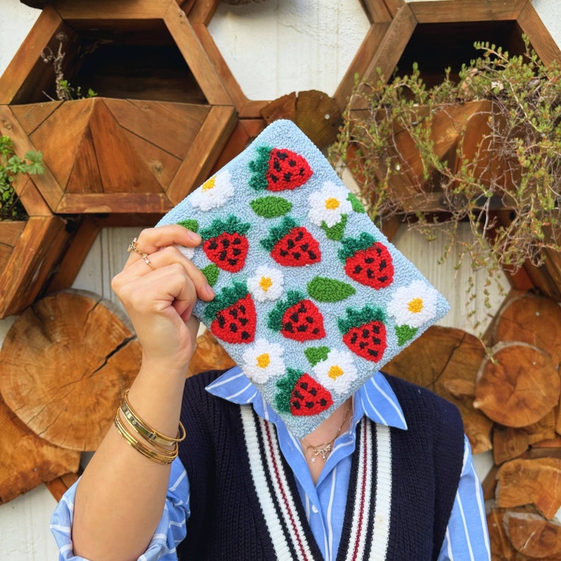 Peut inclure: Une pochette bleu clair avec un motif floral et des fraises. Le sac est fait d'un tissu doux et textur&eacute; et poss&egrave;de une fermeture &eacute;clair.