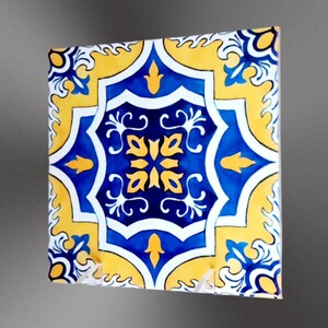 Può includere: Una piastrella quadrata in ceramica con un motivo geometrico blu e giallo. La piastrella ha uno sfondo bianco con un centro blu e accenti gialli.