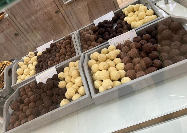 May include: Four wooden trays filled with various chocolate truffles. The trays are labeled "Bailey's", "Champagne", and two unlabeled trays. The truffles are white, dark, and milk chocolate.