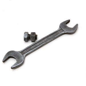 May include: A silver wrench with a black handle and the word "Hansa" printed on it. A silver nut and bolt are also in the image.