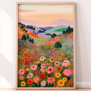 May include: A framed art print featuring a vibrant landscape painting. The artwork depicts a colorful field of flowers in the foreground, with rolling hills and a sunset sky in the background. The color palette includes pinks, oranges, yellows, and greens.