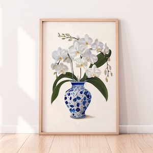 May include: A framed print of a white orchid bouquet in a blue and white porcelain vase. The vase has a floral pattern.